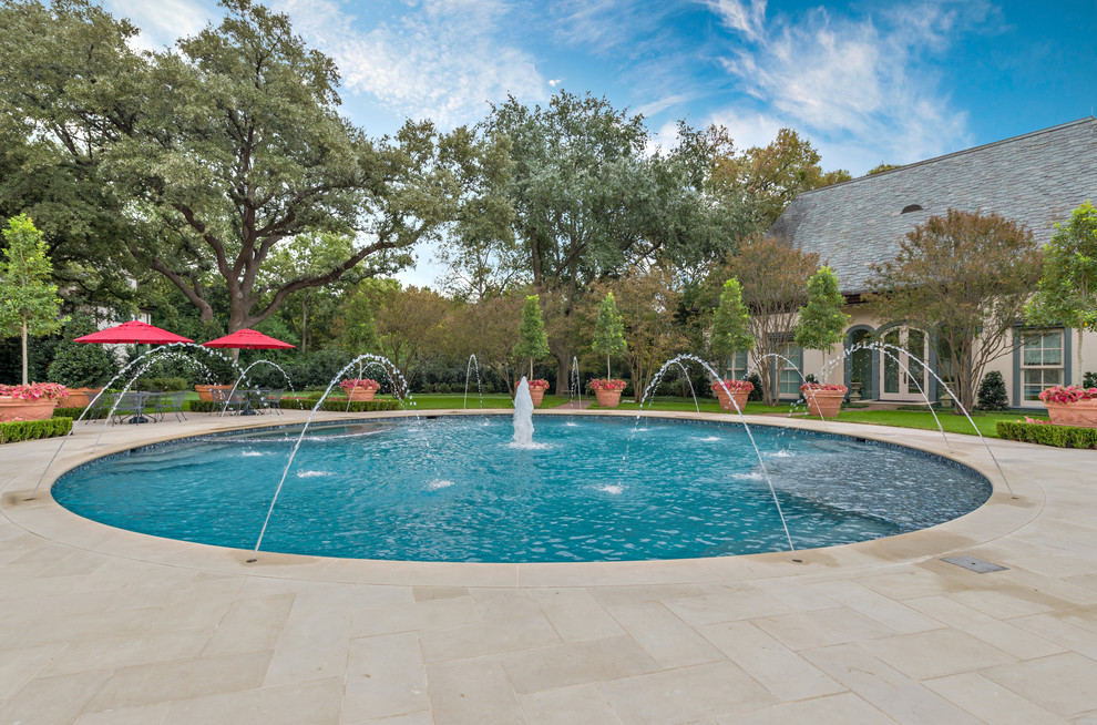 Inspiration for a traditional round pool in Dallas with a water feature.