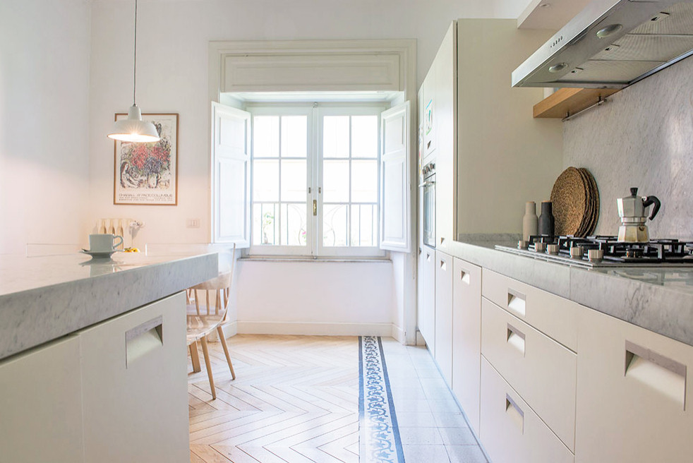 Foto di una grande cucina nordica chiusa con lavello integrato, ante lisce, ante bianche, top in marmo, paraspruzzi in marmo, elettrodomestici in acciaio inossidabile e parquet chiaro