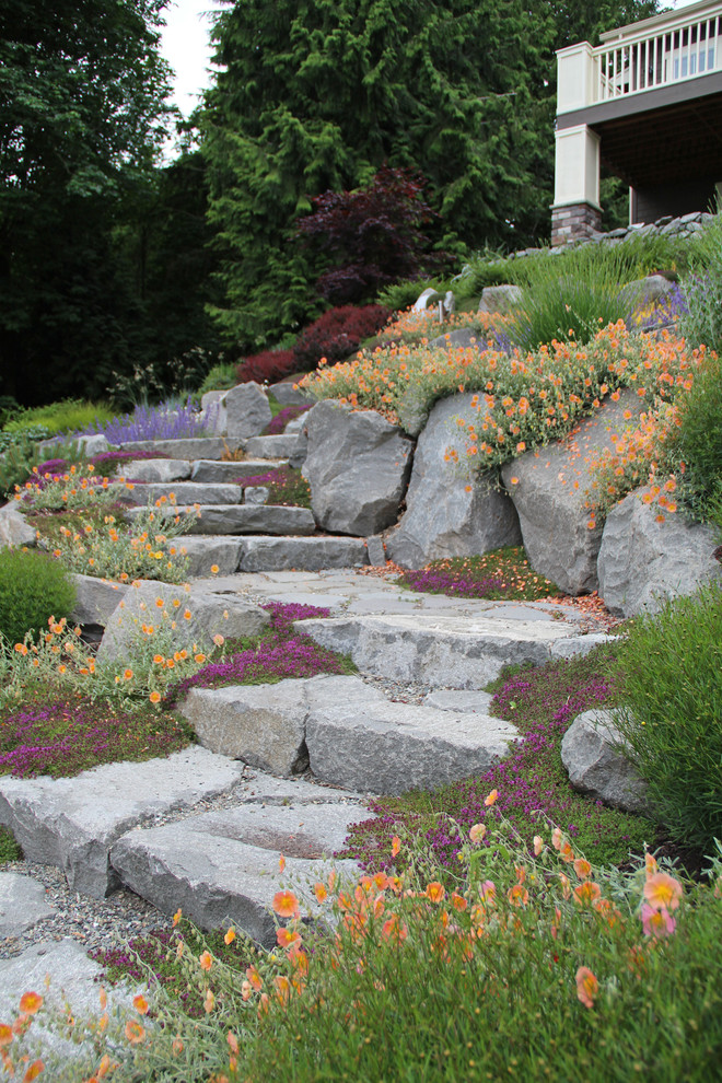 This is an example of a traditional sloped garden in Seattle with natural stone pavers.