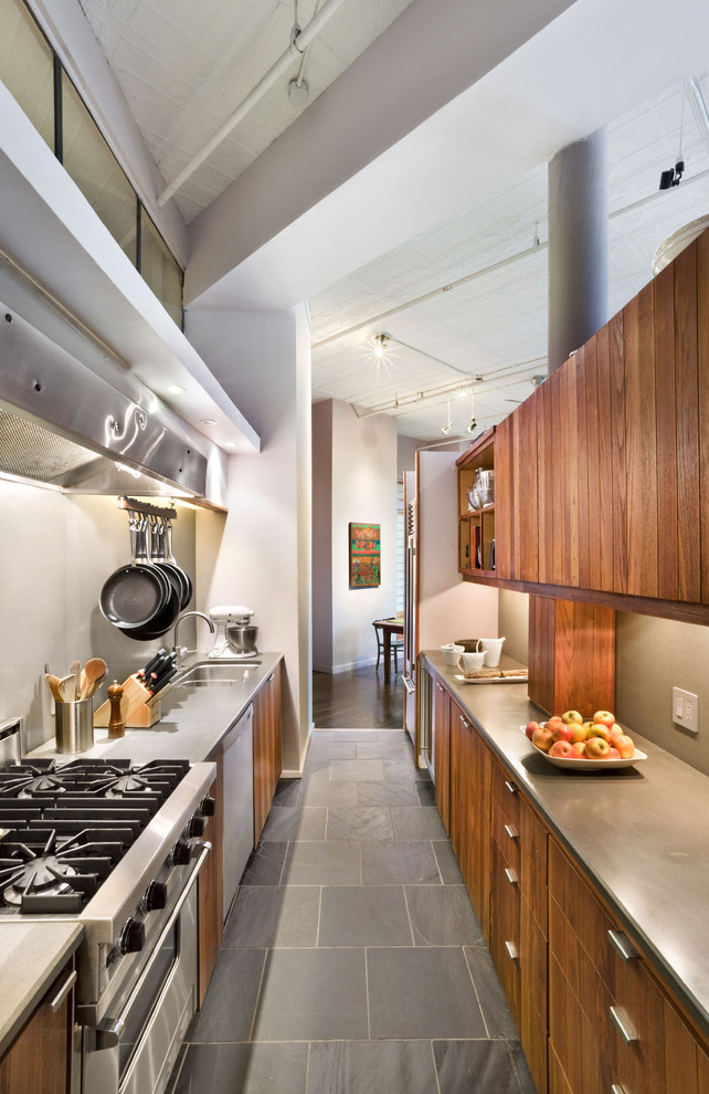 Design ideas for an industrial galley separate kitchen in New York with stainless steel appliances, an undermount sink, flat-panel cabinets, medium wood cabinets and slate floors.