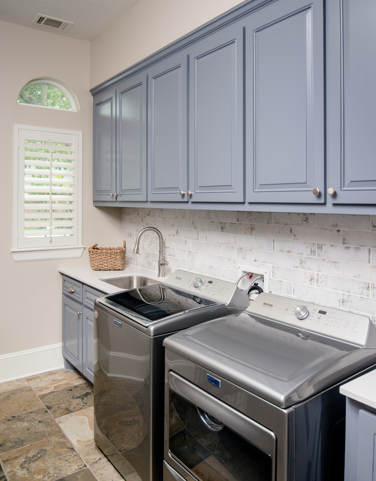 Inspiration for a mid-sized transitional galley dedicated laundry room in Houston with an undermount sink, raised-panel cabinets, beige walls, slate floors, a side-by-side washer and dryer, multi-coloured floor, white benchtop, blue cabinets and quartz benchtops.