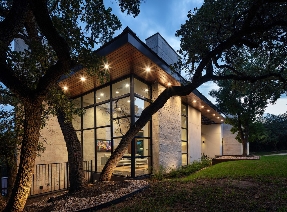 This is an example of a contemporary two-storey glass brown house exterior in Austin with a flat roof.