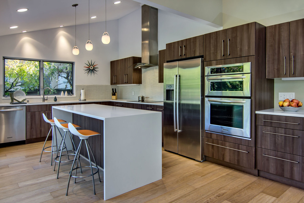 Photo of a midcentury l-shaped eat-in kitchen in San Francisco with a double-bowl sink, flat-panel cabinets, medium wood cabinets, quartz benchtops, grey splashback and stainless steel appliances.