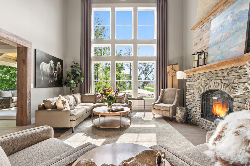 Design ideas for a country family room in Columbus with grey walls, a standard fireplace, a stone fireplace surround, no tv and brown floor.