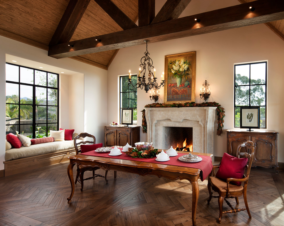 This is an example of a dining room in Santa Barbara with beige walls, dark hardwood floors and a standard fireplace.
