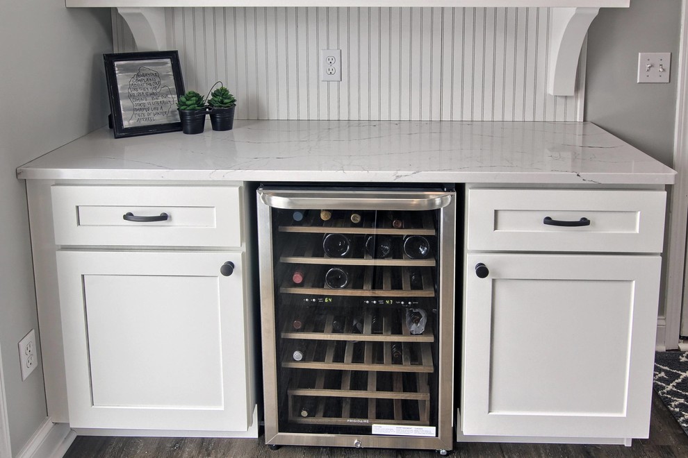 Inspiration for a mid-sized transitional l-shaped vinyl floor eat-in kitchen remodel with a farmhouse sink, shaker cabinets, white cabinets, quartz countertops, white backsplash, stone tile backsplash, stainless steel appliances and an island