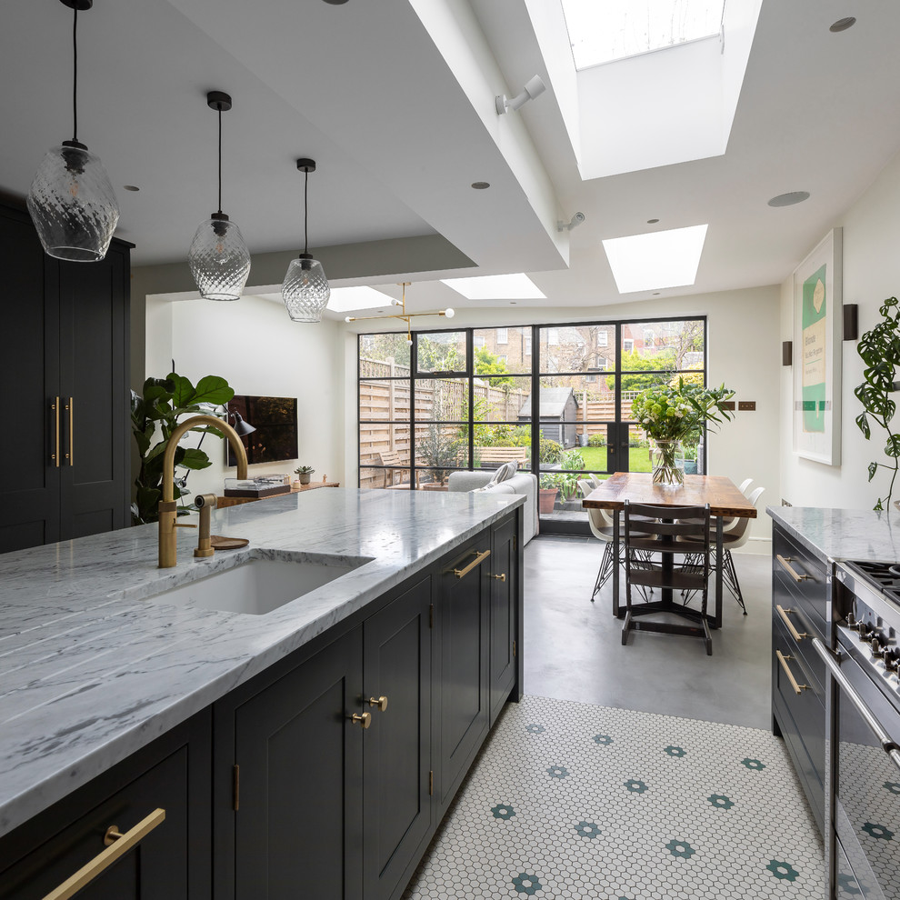 Mid-sized contemporary u-shaped eat-in kitchen in London with an integrated sink, shaker cabinets, green cabinets, marble benchtops, white splashback, marble splashback, stainless steel appliances, porcelain floors, with island, grey floor and white benchtop.