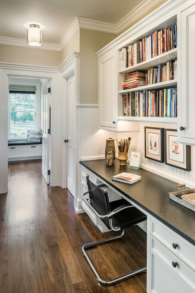 This is an example of a traditional home office in Providence with beige walls, dark hardwood floors, a built-in desk and brown floor.