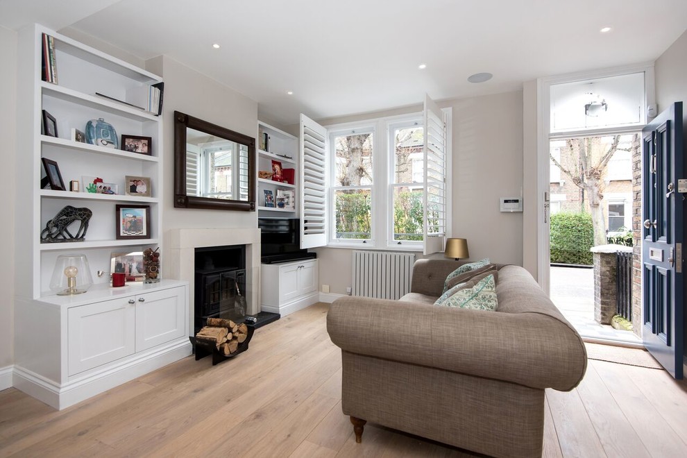 Mid-sized transitional living room in London with grey walls, light hardwood floors, a standard fireplace, a stone fireplace surround and brown floor.