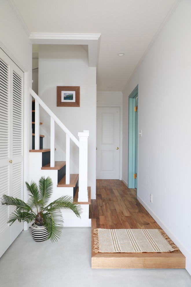 Photo of a beach style entryway in Other with white walls, concrete floors and grey floor.