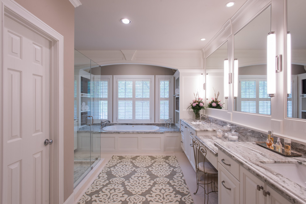 Drop-in bathtub - large traditional master porcelain tile limestone floor drop-in bathtub idea in Houston with raised-panel cabinets, white cabinets, white walls, an undermount sink, quartz countertops and a hinged shower door