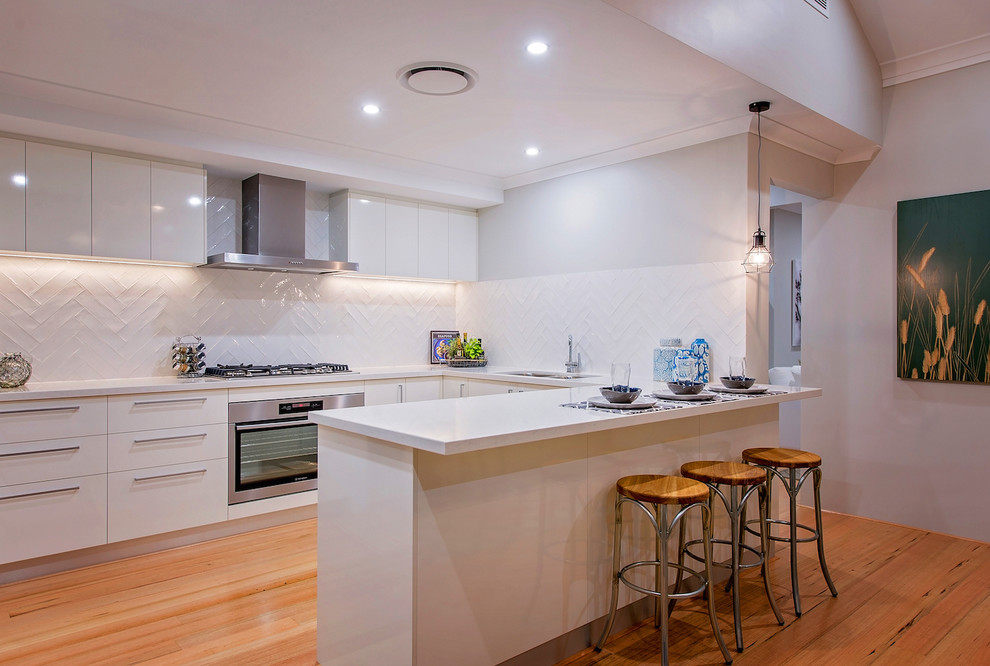 Photo of a large contemporary u-shaped eat-in kitchen in Perth with a double-bowl sink, flat-panel cabinets, yellow cabinets, white splashback, ceramic splashback, stainless steel appliances, vinyl floors and with island.