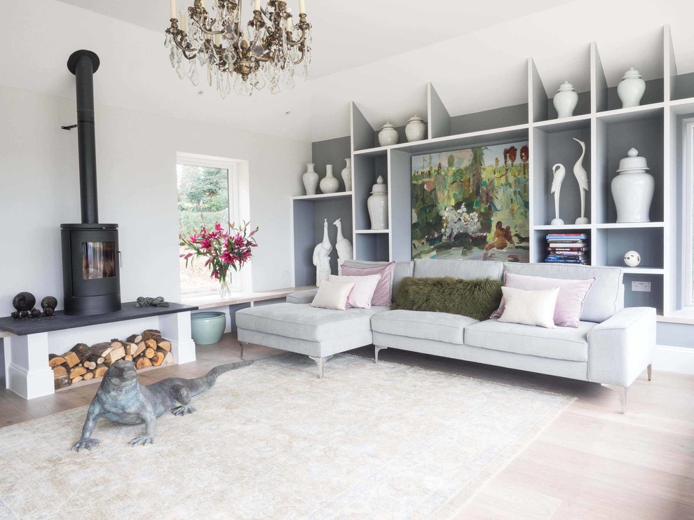 Design ideas for a mid-sized transitional enclosed living room in Gloucestershire with grey walls, light hardwood floors and a wood stove.