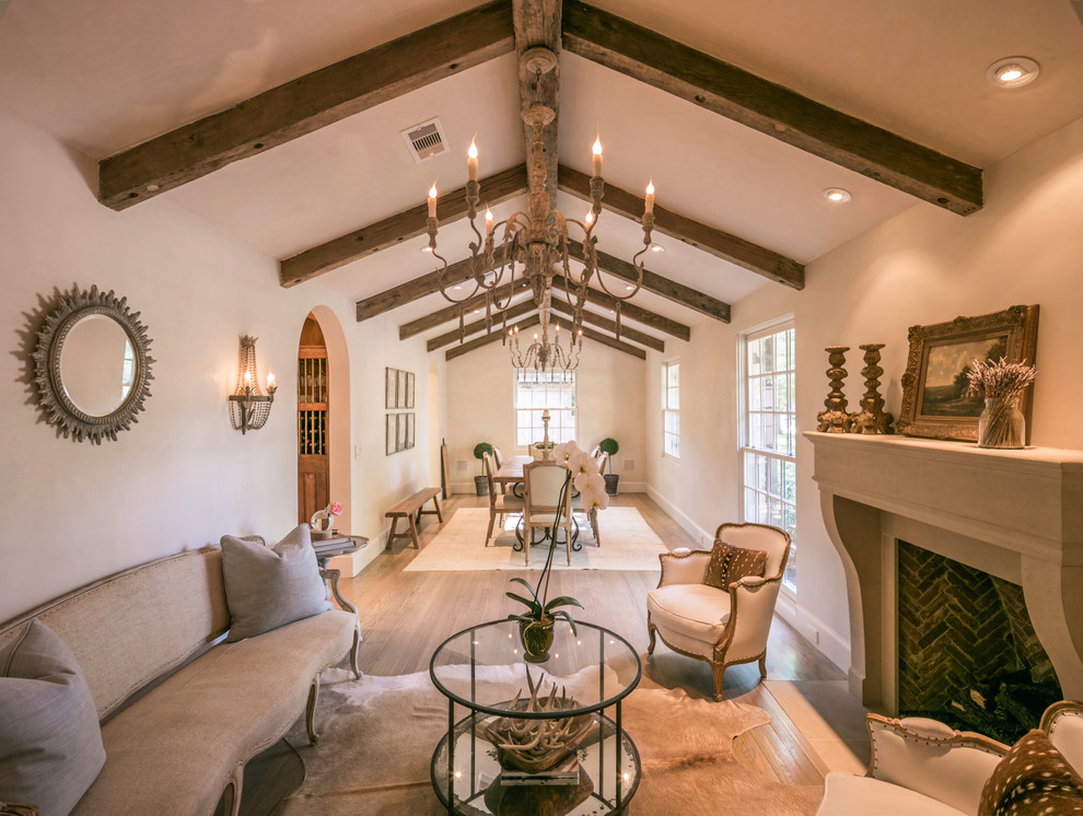 Photo of a mid-sized mediterranean formal open concept living room in Houston with white walls, light hardwood floors, no tv, a standard fireplace and a brick fireplace surround.