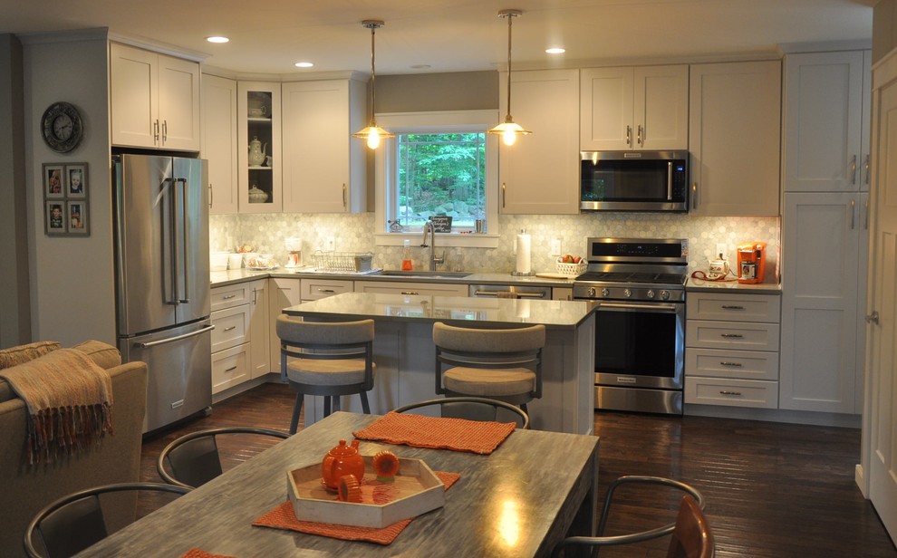 Small transitional l-shaped eat-in kitchen in Boston with an undermount sink, recessed-panel cabinets, white cabinets, quartz benchtops, white splashback, porcelain splashback, stainless steel appliances, dark hardwood floors, with island, brown floor and grey benchtop.