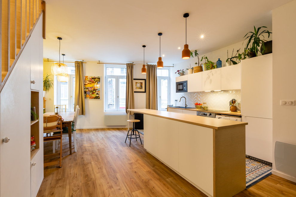 パリにあるお手頃価格の中くらいなコンテンポラリースタイルのおしゃれなキッチン (シングルシンク、フラットパネル扉のキャビネット、白いキャビネット、木材カウンター、白いキッチンパネル、テラコッタタイルのキッチンパネル、パネルと同色の調理設備、セメントタイルの床、マルチカラーの床、ベージュのキッチンカウンター) の写真