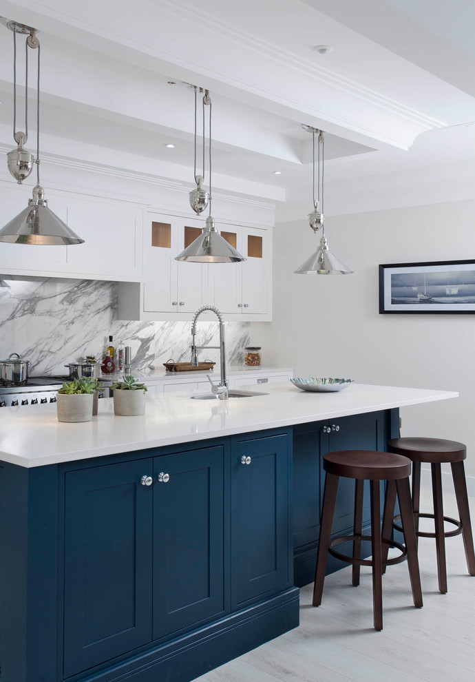 Mid-sized transitional l-shaped open plan kitchen in Other with an undermount sink, shaker cabinets, grey cabinets, quartzite benchtops, grey splashback, marble splashback, stainless steel appliances, light hardwood floors, with island and white floor.