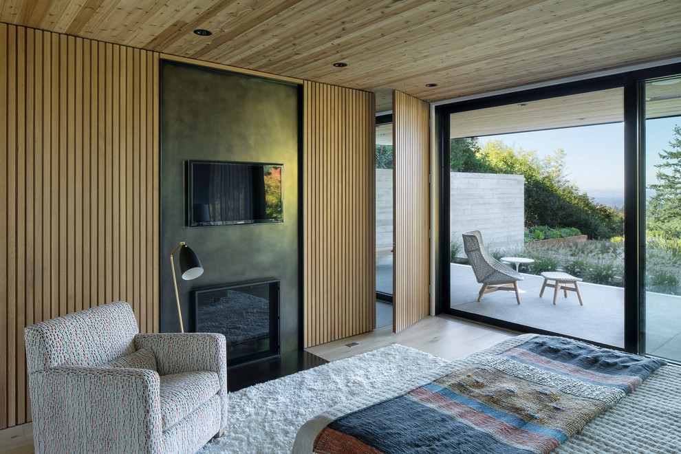 Inspiration for a midcentury master bedroom in Portland with light hardwood floors, a standard fireplace and beige floor.