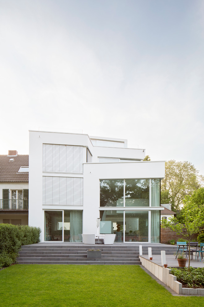 Design ideas for a large contemporary three-storey white exterior in Cologne with a flat roof.