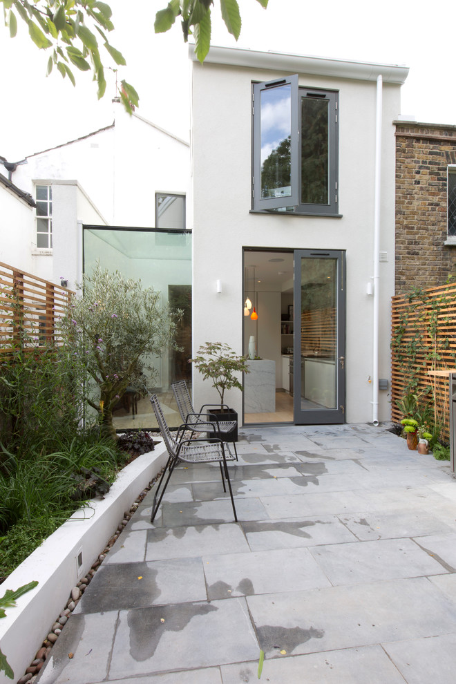 Design ideas for a mid-sized contemporary two-storey stucco white townhouse exterior in London.