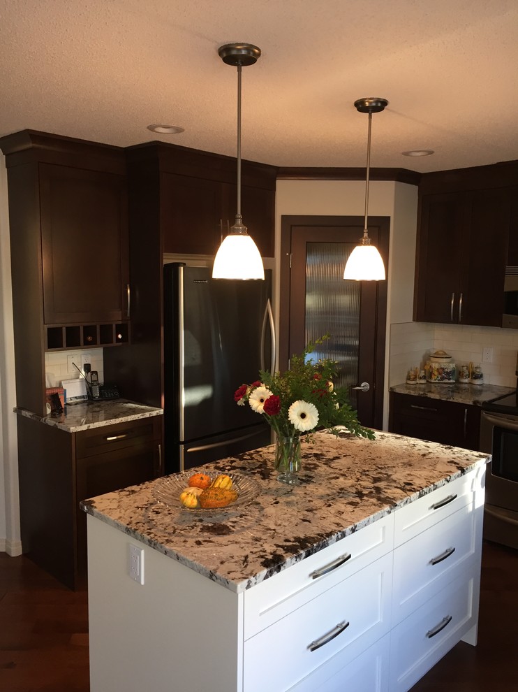 Example of a mid-sized classic u-shaped dark wood floor and brown floor eat-in kitchen design in Calgary with an undermount sink, shaker cabinets, dark wood cabinets, granite countertops, white backsplash, subway tile backsplash, stainless steel appliances and an island