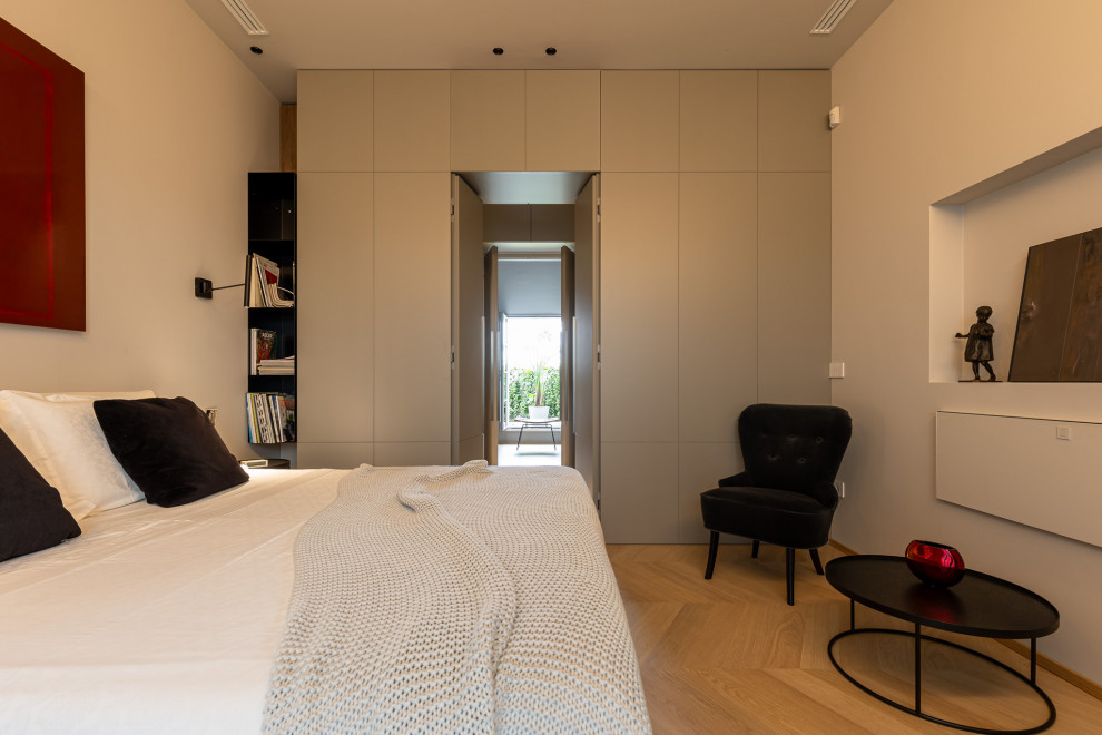 Modernes Schlafzimmer mit weißer Wandfarbe, hellem Holzboden und beigem Boden in Mailand