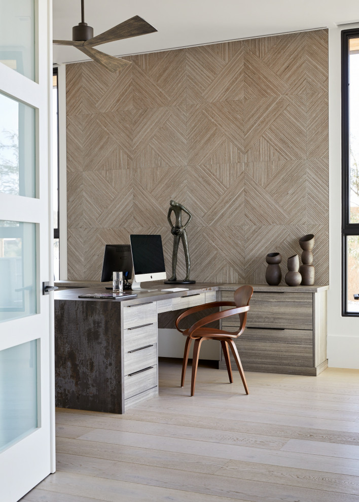 Diseño de despacho grande con paredes marrones, suelo de madera clara, escritorio empotrado, suelo beige y madera