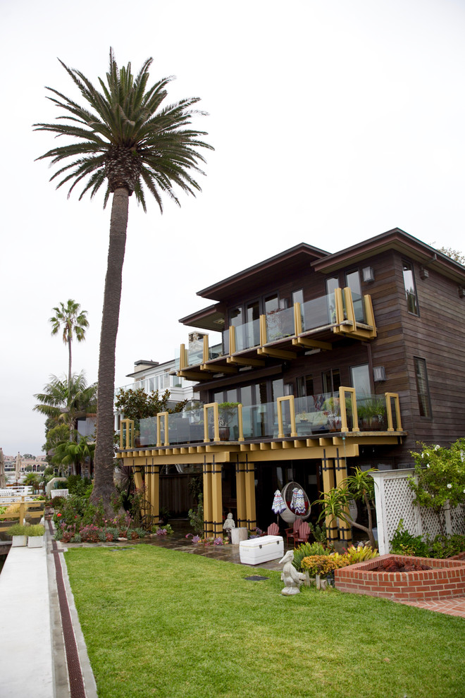 This is an example of a mid-sized tropical three-storey brown exterior in Orange County with wood siding and a flat roof.