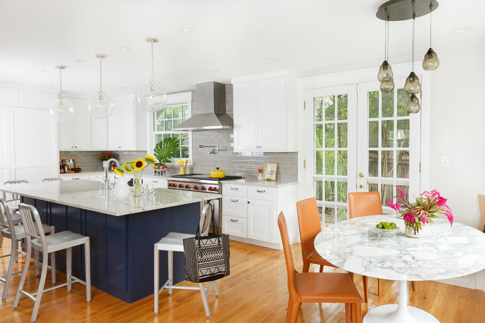 Transitional l-shaped medium tone wood floor eat-in kitchen photo in Austin with shaker cabinets, white cabinets, gray backsplash, subway tile backsplash, stainless steel appliances and an island