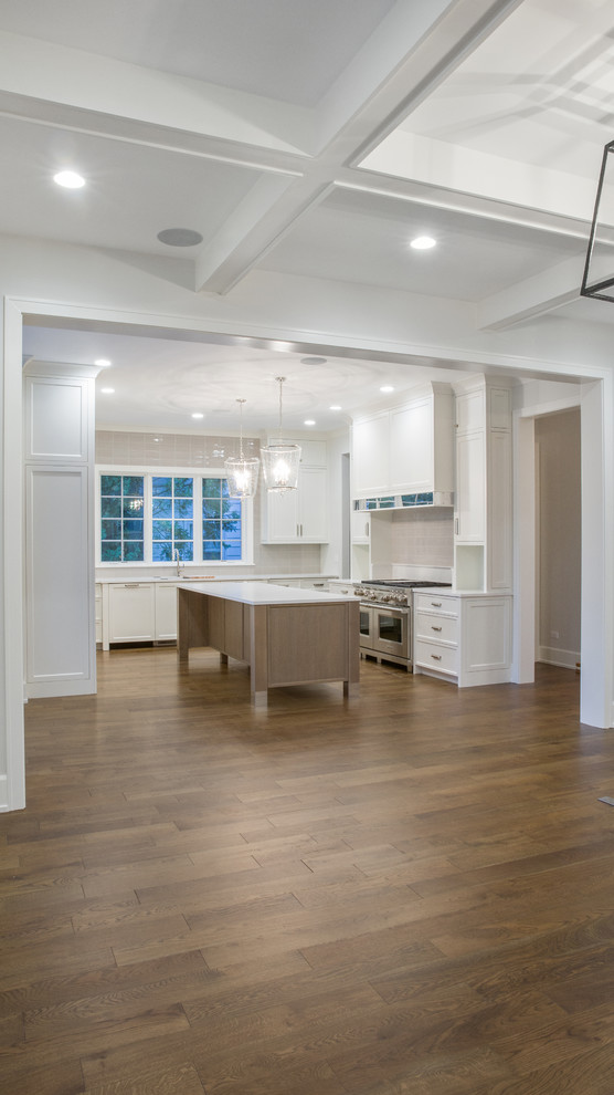 Design ideas for a large modern galley kitchen in Chicago with a single-bowl sink, beaded cabinets, white cabinets, white splashback, ceramic splashback, stainless steel appliances, medium hardwood flooring, an island, brown floors, white worktops and a coffered ceiling.