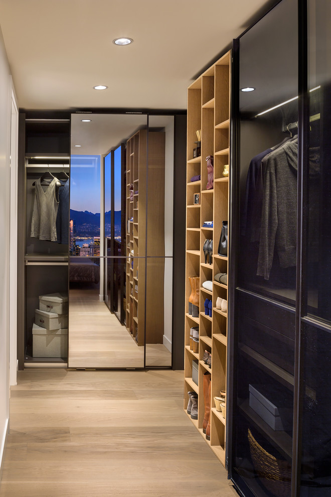 Inspiration for a mid-sized contemporary gender-neutral walk-in wardrobe in Vancouver with glass-front cabinets, light wood cabinets, light hardwood floors and brown floor.