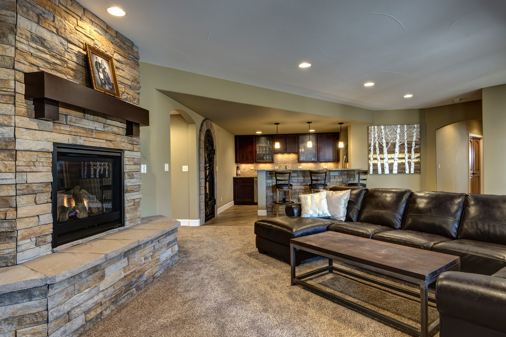Photo of an expansive transitional walk-out basement in Denver with beige walls, carpet, a corner fireplace, a stone fireplace surround and brown floor.