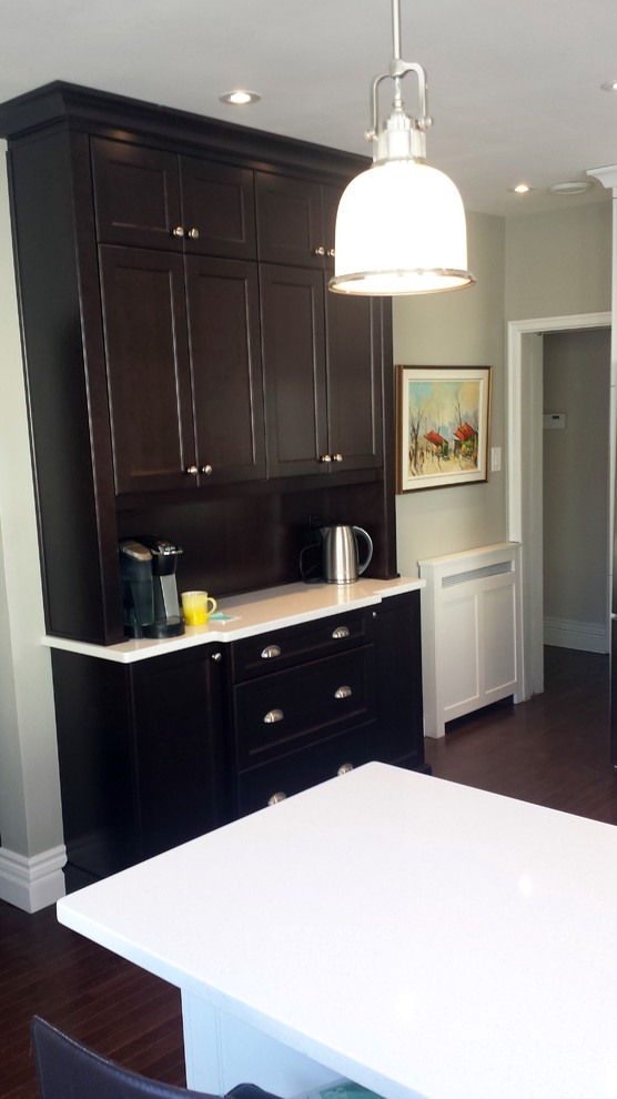 Enclosed kitchen - mid-sized transitional u-shaped dark wood floor enclosed kitchen idea in Ottawa with an undermount sink, shaker cabinets, white cabinets, quartz countertops, white backsplash, subway tile backsplash, stainless steel appliances and a peninsula