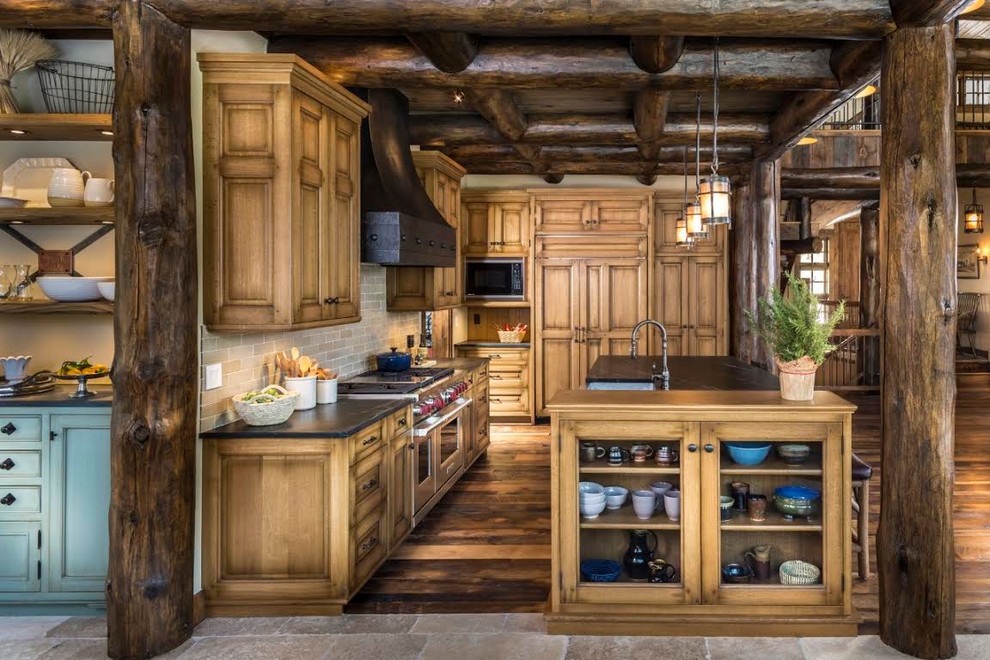 Inspiration for a large rustic l-shaped dark wood floor kitchen remodel in Denver with a farmhouse sink, raised-panel cabinets, medium tone wood cabinets, soapstone countertops, beige backsplash, subway tile backsplash, stainless steel appliances and an island