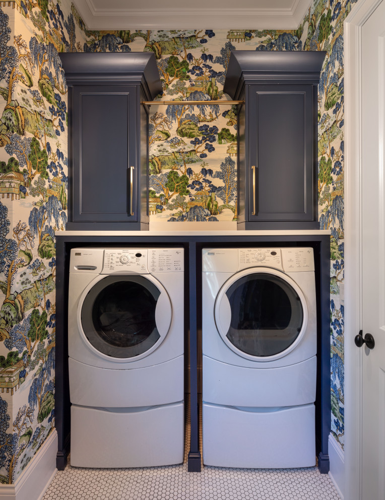 Inspiration for a mid-sized transitional dedicated laundry room in Atlanta with an undermount sink, shaker cabinets, blue cabinets, solid surface benchtops, multi-coloured walls, porcelain floors, a side-by-side washer and dryer, white floor, white benchtop and wallpaper.