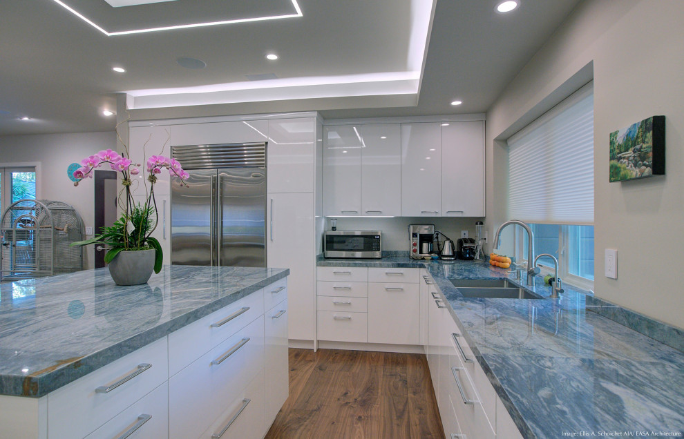 This is an example of a mid-sized contemporary u-shaped open plan kitchen in San Francisco with an undermount sink, flat-panel cabinets, white cabinets, quartzite benchtops, blue splashback, stone slab splashback, stainless steel appliances, medium hardwood floors, with island, blue benchtop and recessed.