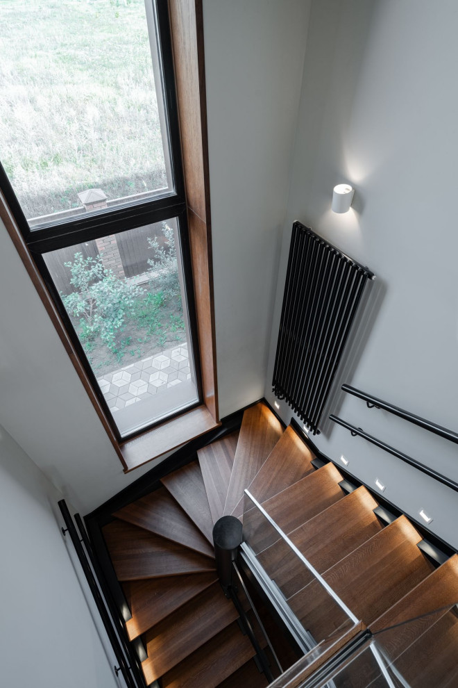 Идея дизайна: угловая металлическая лестница среднего размера в современном стиле с деревянными ступенями и металлическими перилами