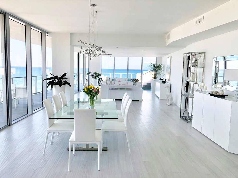 Photo of a large beach style open plan dining in Miami with white walls, porcelain floors, no fireplace and grey floor.