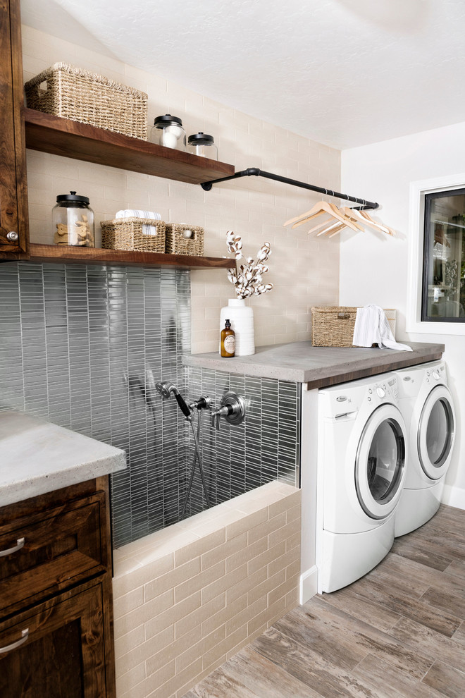 Photo of a mid-sized country single-wall dedicated laundry room in Sacramento with a drop-in sink, raised-panel cabinets, dark wood cabinets, concrete benchtops, white walls, medium hardwood floors, a side-by-side washer and dryer, brown floor and grey benchtop.