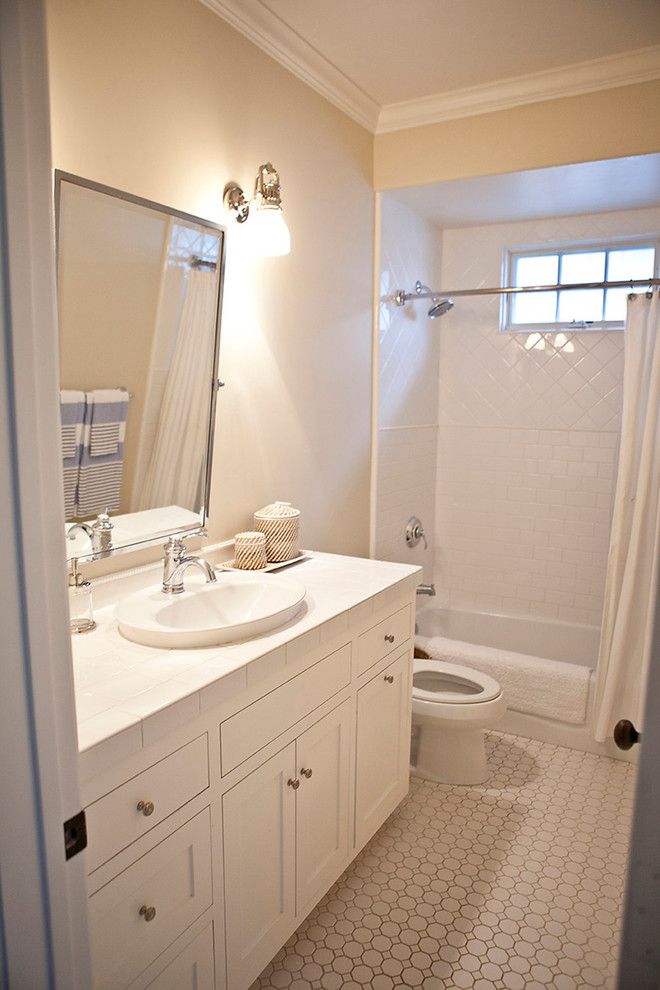 Mid-sized beach style kids bathroom in San Diego with a drop-in sink, shaker cabinets, white cabinets, tile benchtops, an alcove tub, a shower/bathtub combo, a one-piece toilet, yellow tile, ceramic tile, beige walls and ceramic floors.