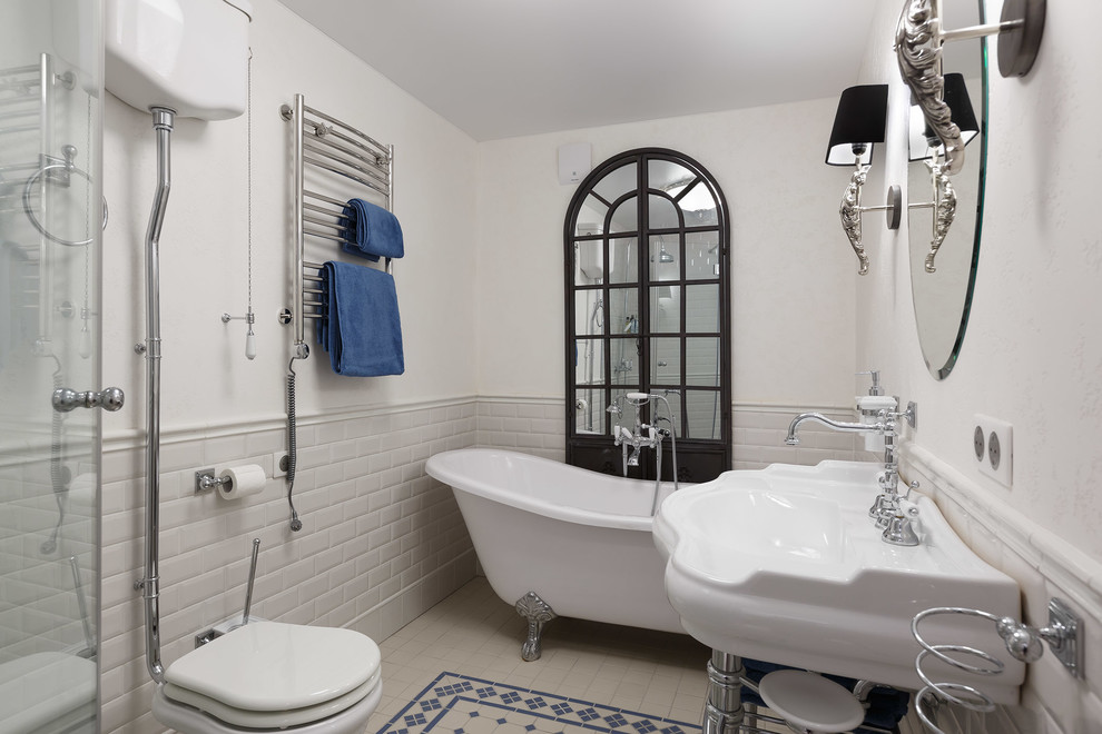 This is an example of a mid-sized traditional master bathroom in Saint Petersburg with a claw-foot tub, white tile, subway tile, cement tiles, a console sink, a two-piece toilet and white walls.