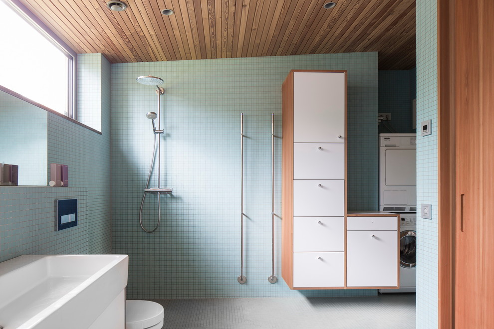 Mid-sized scandinavian 3/4 bathroom in Malmo with flat-panel cabinets, white cabinets, an open shower, blue tile, gray tile, an integrated sink, mosaic tile, green walls, mosaic tile floors, an open shower and a laundry.