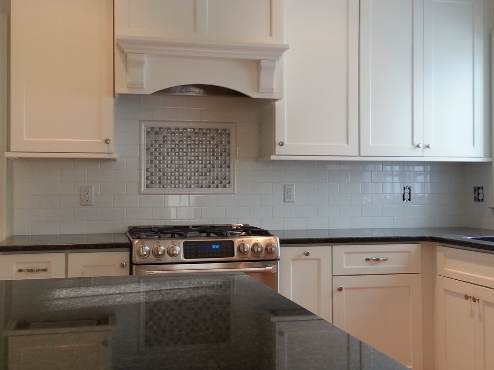 Mid-sized l-shaped light wood floor eat-in kitchen photo in Newark with a drop-in sink, raised-panel cabinets, white cabinets, granite countertops, white backsplash, subway tile backsplash, stainless steel appliances and an island