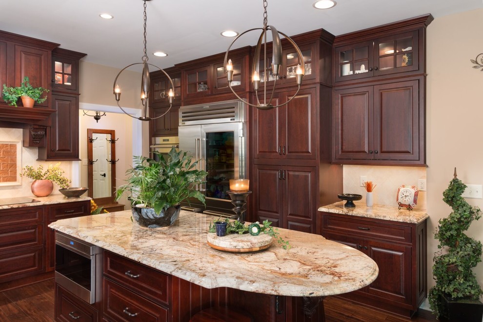 This is an example of a large traditional l-shaped eat-in kitchen in San Francisco with brown floor, a drop-in sink, raised-panel cabinets, dark wood cabinets, granite benchtops, beige splashback, stone tile splashback, stainless steel appliances, dark hardwood floors, with island and beige benchtop.