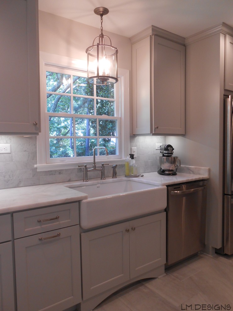 Inspiration for a transitional galley porcelain tile eat-in kitchen remodel with a farmhouse sink, recessed-panel cabinets, gray cabinets, marble countertops, stone tile backsplash, stainless steel appliances and a peninsula