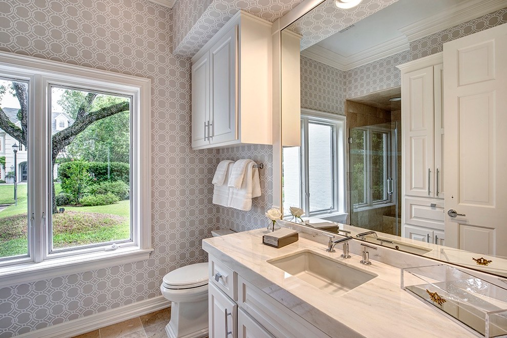 Large transitional kids bathroom in Houston with raised-panel cabinets, white cabinets, an open shower, a one-piece toilet, gray tile, porcelain tile, grey walls, travertine floors, a drop-in sink, marble benchtops, grey floor and a hinged shower door.