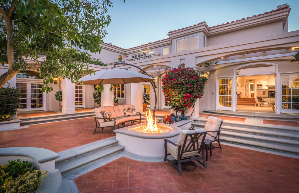Design ideas for a mediterranean courtyard patio in Orange County with a fire feature, tile and no cover.