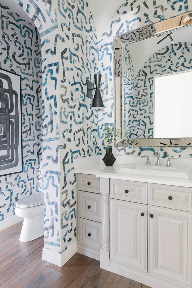 Bathroom - transitional dark wood floor, brown floor, single-sink and wallpaper bathroom idea in Phoenix with raised-panel cabinets, gray cabinets, multicolored walls, a drop-in sink, white countertops and a built-in vanity