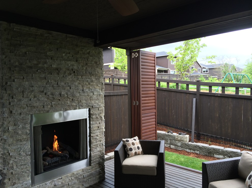 This is an example of a transitional backyard patio in Dallas with a fire feature, decking and an awning.