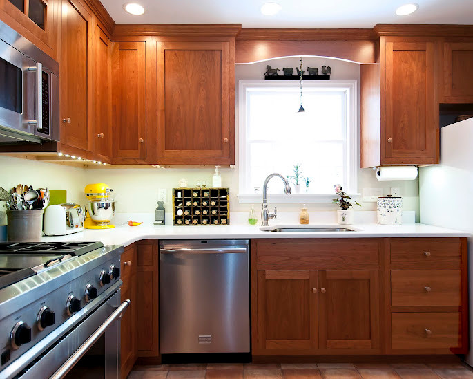 This is an example of a large traditional l-shaped eat-in kitchen in Boston with an undermount sink, shaker cabinets, dark wood cabinets, solid surface benchtops, stainless steel appliances, terra-cotta floors, with island and red floor.